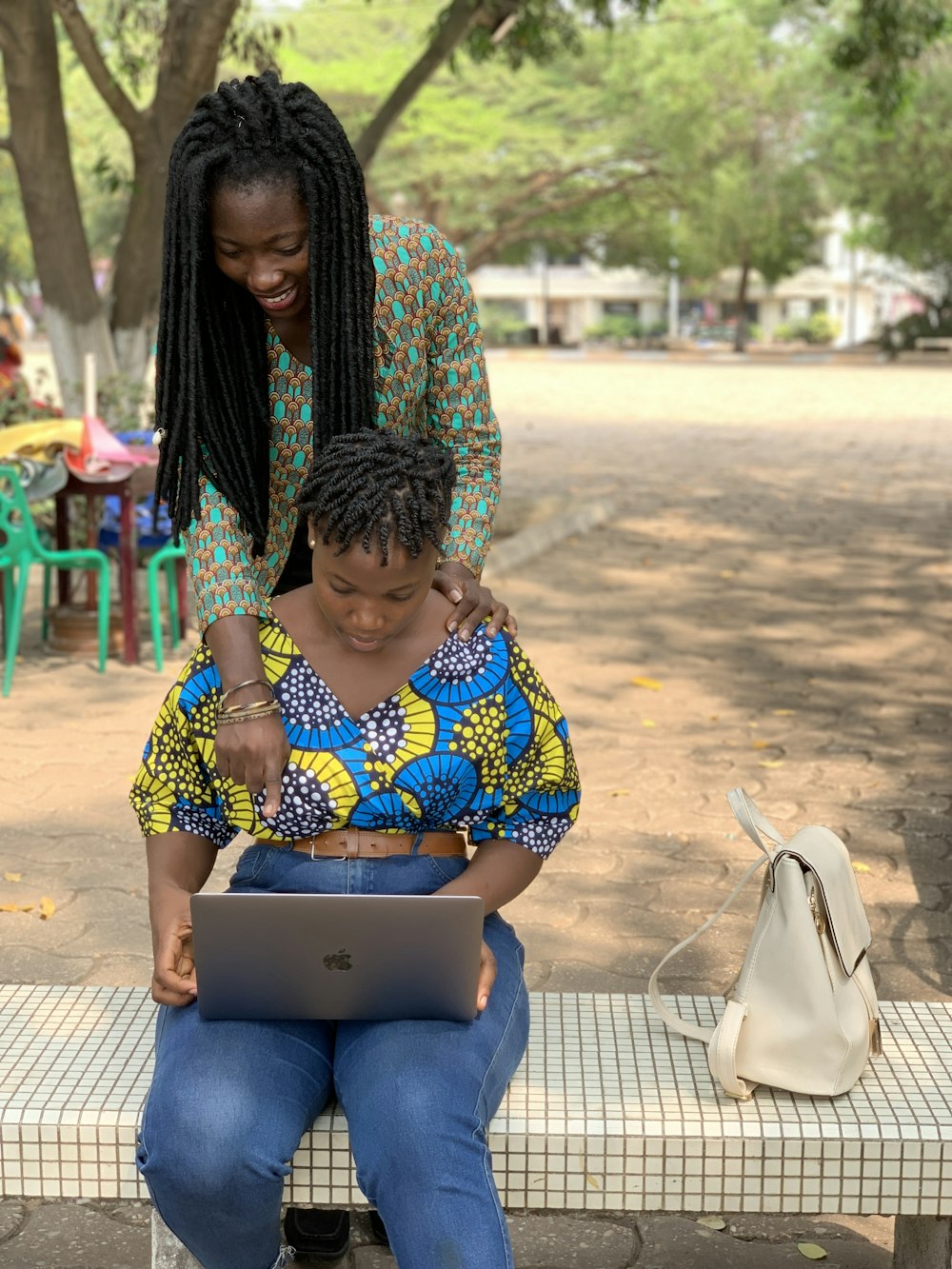A mentor helping a student with her laptop outdoors