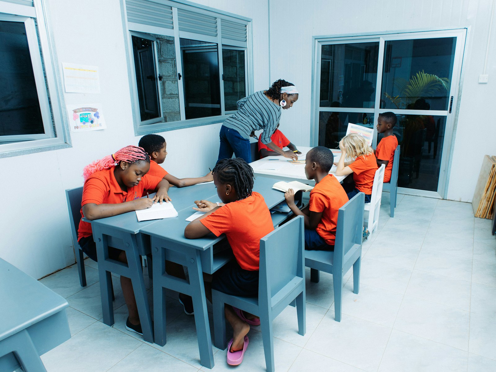 A teacher helping a class of children at their tables